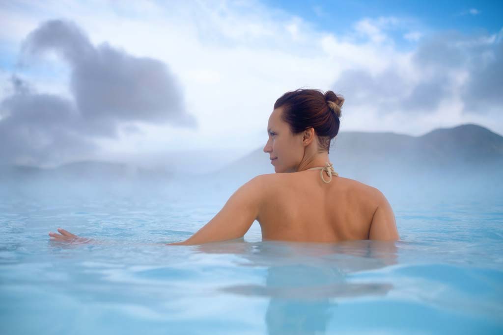 Beautiful woman bathing in geothermal hot spring in Iceland